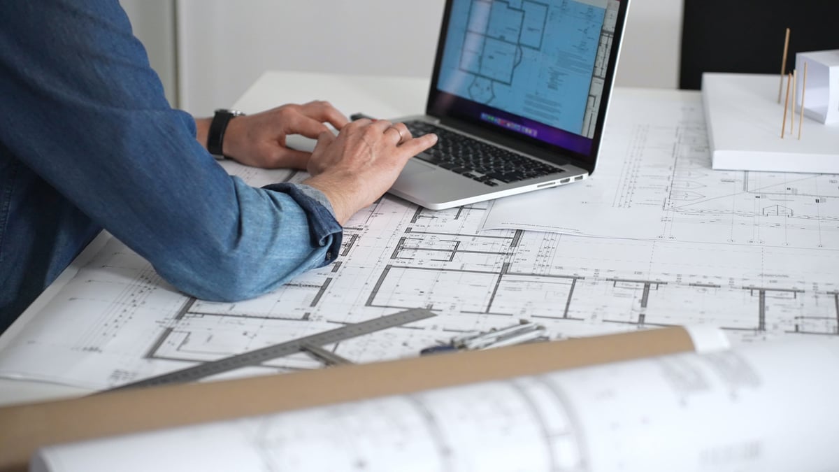 Architect reviewing building plans at a drafting desk